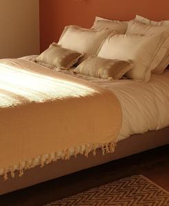 - un lit avec des draps et des oreillers blancs dans l'établissement Le Grand Jardin, à Port-Saint-Père