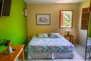 a bedroom with a bed and green walls at Pousada Bemvirá in Arraial d'Ajuda