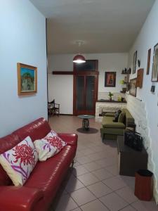 波佐利的住宿－la casa di Vi，客厅配有红色真皮沙发和壁炉
