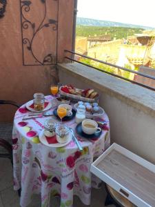 een tafel met eten en drinken op een balkon bij Maison d'hôtes Une hirondelle en Provence in Roussillon