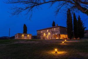 a building with lights in a field at night at Podere La Piscina- Acqua Termale e Relax in San Casciano dei Bagni