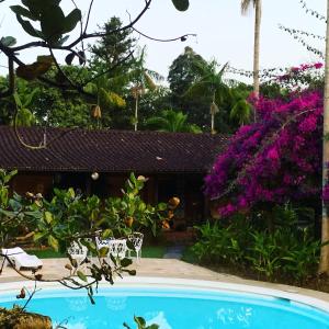 una piscina en un jardín con flores púrpuras en Pousada Penedo, en Penedo