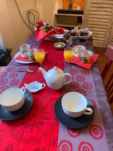 une table avec un service à thé sur un tissu de table rouge dans l'établissement Maison d'hôtes Une hirondelle en Provence, à Roussillon