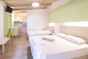 two beds in a room with a kitchen at Apartments Korakakis Beach in Finikounta