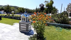 a garden with a bird house and flowers at House Anna Houhlia in Vourvourou