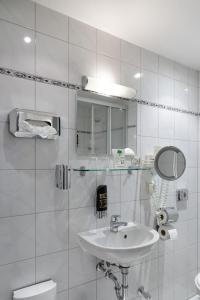 a white bathroom with a sink and a mirror at Löwenbräu am Kohlmarkt in Wernigerode