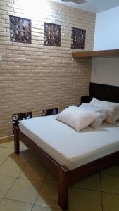 uma cama grande num quarto com uma parede de tijolos em Chales Virena em Ubatuba