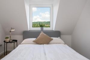 a bedroom with a white bed with a window at CASSEL LOFTS - Stilvolles Loft im Grünen mit Balkon nahe VW-Werk in Kassel