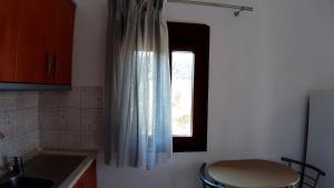 a kitchen with a window and a sink and a stool at House Anna Houhlia in Vourvourou