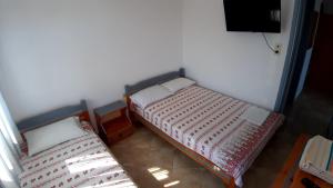 two twin beds in a room with a tv at House Anna Houhlia in Vourvourou