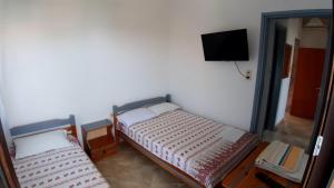 a room with two beds and a tv on the wall at House Anna Houhlia in Vourvourou
