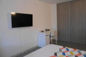a room with a bed with a television on the wall at Particulier loue T3 en rez de jardin à 30 mètres de la plage avec un double box in La Ciotat