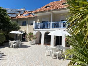 a patio with tables and umbrellas in front of a house at Logis Les Vagues in Biscarrosse-Plage