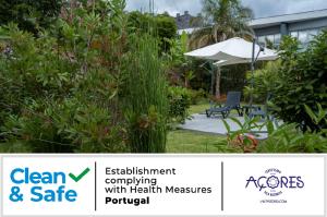 een bord voor een tuin met een bank en een paraplu bij Casa da Quinta in Vila Franca do Campo
