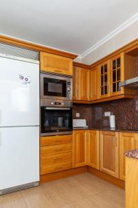 a kitchen with wooden cabinets and a white refrigerator at Apartamento Sambala in Ontinyent