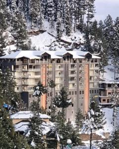 a large building with snow on top of it at Bellevue Luxury Apartments Nathia Gali in Nathia Gali