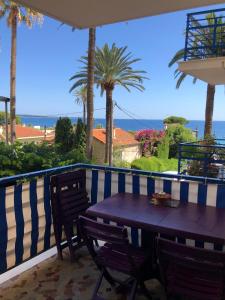 een houten tafel en stoelen op een balkon met uitzicht op de oceaan bij Cannes Les Pins in Cannes