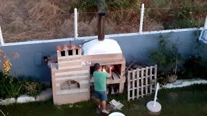 a man is constructing a wood fired oven at House Anna Houhlia in Vourvourou