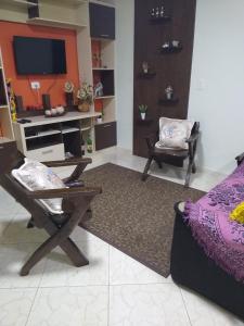 a living room with a tv and a chair and a couch at Pousada Pica Pau in Urubici