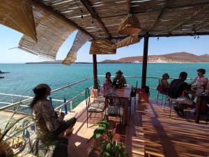 a group of people sitting at tables on a deck overlooking the water at Club Cantamar Beach Hotel & Marina in La Paz +49 photos