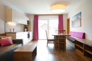 ein Wohnzimmer mit Couch und Tisch und eine Küche in der Unterkunft Bergfink apartments in Flachau