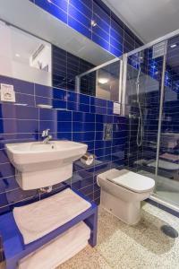 a blue tiled bathroom with a sink and a toilet at Hostal Albany in León