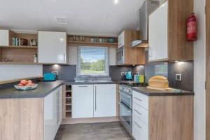 a kitchen with white appliances and wooden cabinets at Premium Chalet at Newquay Away Resorts MV7 in Newquay