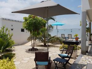 um pátio com cadeiras e uma mesa com um guarda-sol em African Jaja villa Piscine-Climatisation em Poponguine