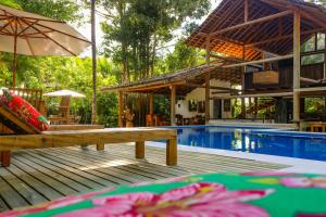 a resort with a pool and a deck with an umbrella at Pousada Hibisco in Trancoso