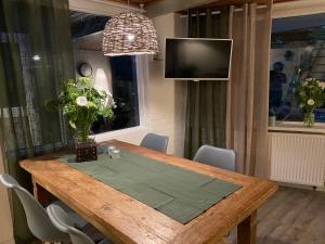 a dining room table with chairs and a television at Uniek vakantiehuisje in rustige en groene omgeving in Nieuwe-Niedorp