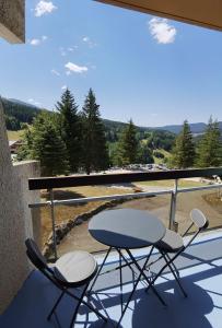 2 Stühle und ein Tisch auf einem Balkon mit Aussicht in der Unterkunft Le balcon de villard in Villard-de-Lans