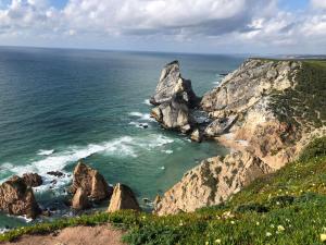 a view of the ocean with rocks in the water at ribeira dos marinheiros amarelo in Sintra