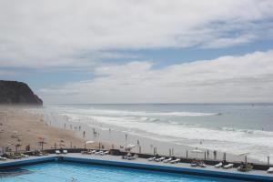 a view of a beach with a swimming pool and the ocean at ribeira dos marinheiros amarelo in Sintra
