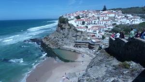 a group of people standing on a cliff near the ocean at ribeira dos marinheiros amarelo in Sintra