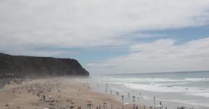 a group of people on a beach near the ocean at ribeira dos marinheiros amarelo in Sintra