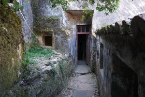 an alley in an old stone building with a red door at ribeira dos marinheiros amarelo in Sintra