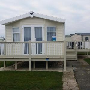 a large house with a porch and a fence at Cosy caravans Sandhills 213 Butlins Skegness resort in Ingoldmells