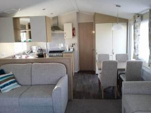 a living room and kitchen with a couch and a table at Cosy caravans Sandhills 213 Butlins Skegness resort in Ingoldmells