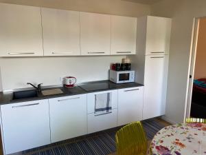 a kitchen with white cabinets and a microwave at Casa sciliar blu centro paese in Völs am Schlern