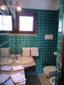 Baño de azulejos verdes con lavabo y aseo en Conca Verde, en Conca Verde