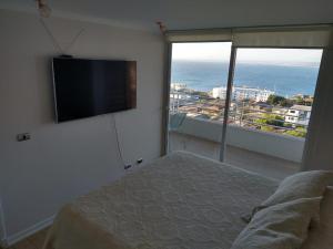 een slaapkamer met een bed en een flatscreen-tv bij DEPARTAMENTO EDIFICIO MARES DE MONTEMAR in Concón +13 foto's