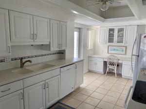 a kitchen with white cabinets and a sink and a chair at Island House Beach Resort 5S in Siesta Key