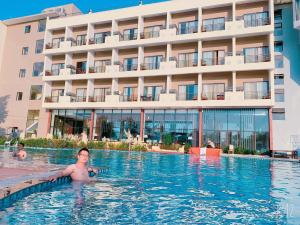 un hombre en una piscina frente a un hotel en Hamya Hotsprings and Resort, en Quảng Ngãi