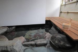a room with a wooden deck and a pond with rocks at Yamaguchi House,Historic Private House with Open-Air Hot springs in Hakone