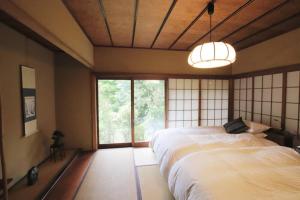 a bedroom with two beds and a large window at Yamaguchi House,Historic Private House with Open-Air Hot springs in Hakone