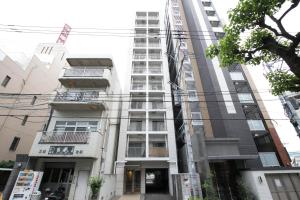 a tall white building with windows and balconies at Chiyo apartment in Fukuoka