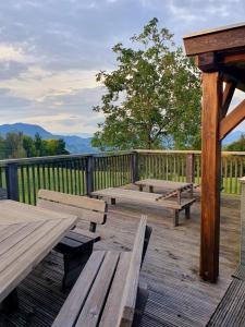 a wooden deck with picnic tables and a fence at Gozdarjeva koča nad Rimskimi Toplicami in Dol pri Hrastniku