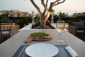 a table with a pizza and a glass of wine at Evripidou Suites in Athens