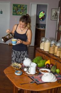 a woman holding a bowl of food in front of a wooden table at Epiphyte B & B in Cape Tribulation