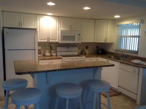 a kitchen with white cabinets and blue stools at Island House Beach Resort 21 in Point O'Rocks